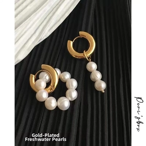 Close-up of asymmetric baroque freshwater pearl earrings with 18K gold plated finish