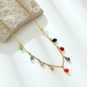 Vintage gold necklace with colorful teardrop zircon pendants on a textured stone base