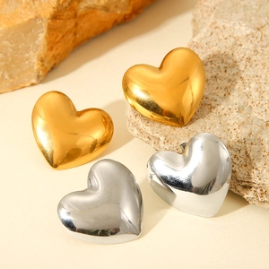 Polished gold and silver heart-shaped stainless steel stud earrings on natural stone