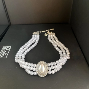 Detailed macro of a triple-strand pearl necklace with a rhinestone oval pendant