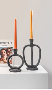 Detailed macro of two modern matte black candle holders with abstract ring shapes