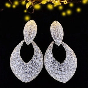 Primer plano de aretes colgantes de plata con circonitas y diseño de hoja brillante