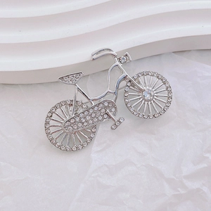 Vintage silver bicycle brooch with sparkling crystals on white textured background