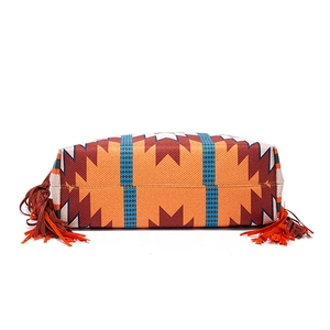 Detailed view of woven geometric patterns and orange fringes on a large shoulder bag
