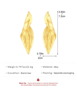 Vista detallada de pendientes de hoja dorada con dimensiones 7,2 x 2 cm y material de aleación