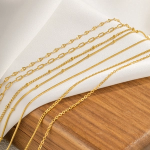 Detailed view of assorted gold chain styles on white silk and wooden base display
