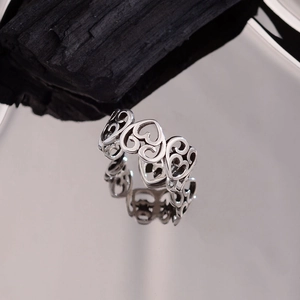 Punk style silver open ring with hollow heart patterns on a reflective mirror base