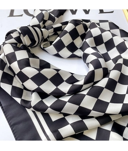 Detail of classic black and white checkerboard silk scarf with elegant drape and texture