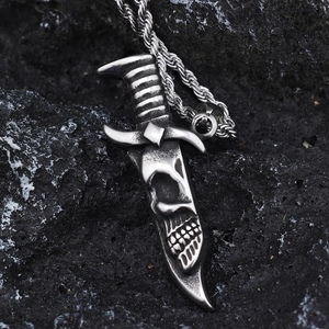 Macro detail of gothic skull dagger pendant in antique silver on volcanic rock background