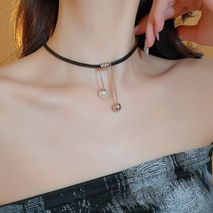 Detail of black leather choker featuring a silver ring with pearl and metal ball pendants