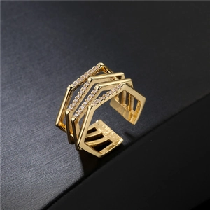 Three-layer geometric gold ring with cubic zirconia stones on matte black surface