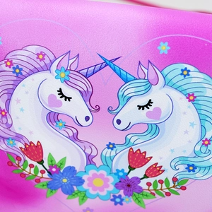 Close-up of pink leather texture with unicorn and flower print for children's handbag