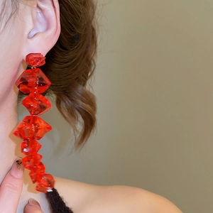 Detailed view of long red acrylic beaded earrings with faceted ice-like crystal texture