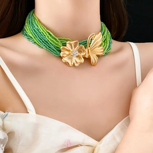 Detail of multi-strand green seed bead necklace with gold floral butterfly rhinestone clasp