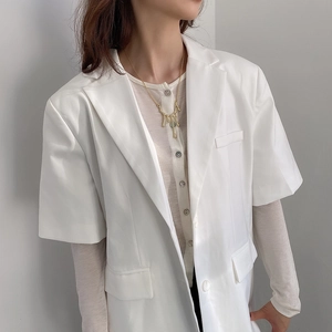 Detail of a minimalist gold dripping pendant necklace worn by a model on grey background