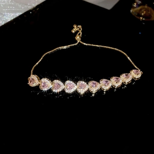 Detailed macro of pink heart gemstones on a golden adjustable bracelet with zircons