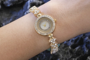 Detail of a women's gold-toned watch with diamond accents on a model's wrist