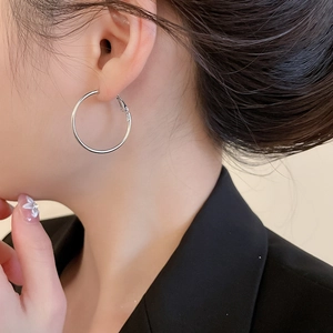 Boucles d'oreilles créoles argentées polies sur mannequin pour un look quotidien