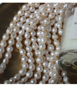 Macro detail of high-luster 6.5-7mm natural baroque pearls on a gold textured tray