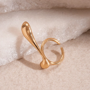 Detailed view of an irregular golden geometric ring set against a natural raw stone background