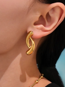 Close-up of 18K gold plated teardrop earrings with a modern curved twist on model