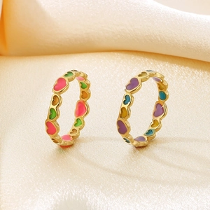 Colorful enamel heart-shaped stainless steel rings on elegant silk background