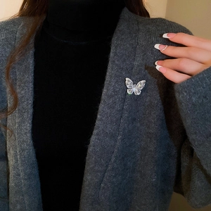 Close-up of sparkling butterfly brooch with teardrop zircon on a grey knit cardigan
