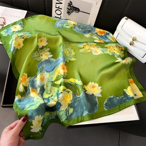 Detail of elegant green silk scarf featuring lotus patterns with stylish magazine props