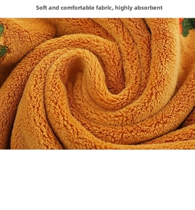 Close-up of soft orange coral fleece fabric with detailed fruit embroidery edge