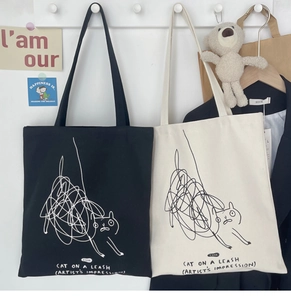 Detail showing task cat graphic print on black and cream canvas tote bags