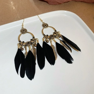 Détail de boucles d'oreilles bohèmes vintage avec cercles en bronze et plumes noires