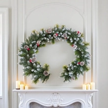 Nahaufnahme eines vereisten Weihnachtskranzes mit Zapfen und Beeren über einem Kamin