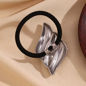 Detail view of the elastic black hair tie with polished silver flame-shaped metal charm