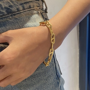 Elegant gold stainless steel curb link bracelet with anchor design worn by a model