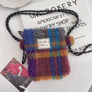 Close-up of colorful checkered plush mini bag with lamb wool texture and pompom details