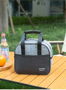 Outdoor picnic cooler bag with gray cationic fabric and black handles on a wooden table