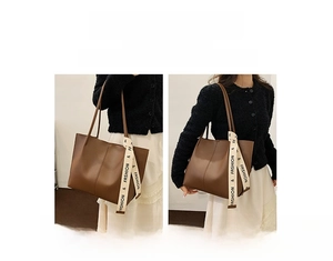 Detail of brown PU leather tote bag with stylish logo strap for hand or shoulder carry