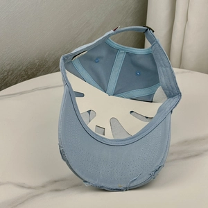 Detail view of light blue distressed baseball cap with metal buckle and worn edges