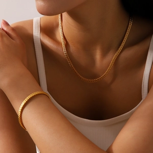 Detail of 18K gold-plated titanium steel woven necklace and bracelet set on a model