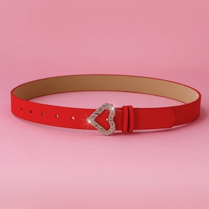 Detail of red leather belt with sparkling heart-shaped buckle on pink background