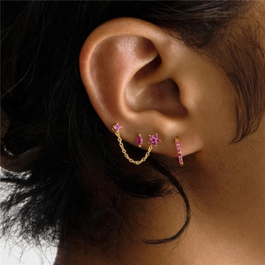 Detail of gold-plated S925 silver earrings set with pink zircon on a model's ear