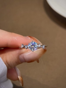 Macro shot of six-prong moissanite ring with wavy diamond-set band on a hand