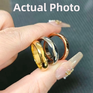 Three minimalist stainless steel rings in gold, silver, and rose gold on a model's hand