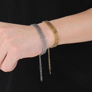 Gros plan de bracelets tennis en acier doré et argenté au poignet avec fermoir mousqueton