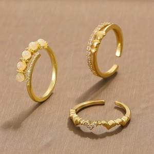 Three gold adjustable rings set with cat-eye opals, hearts, and sparkling crystals