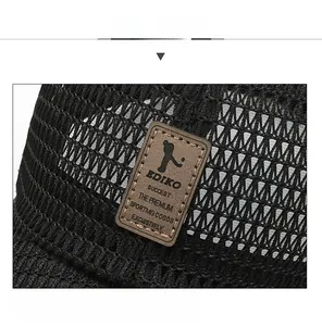 Close-up of breathable mesh fabric and brown leather brand patch on black baseball cap