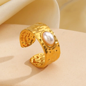 Golden hammered wide ring with oval white pearl inlay on warm beige background