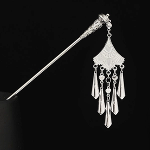 Macro view of silver ethnic hair pin with elegant dangling tassels on black background