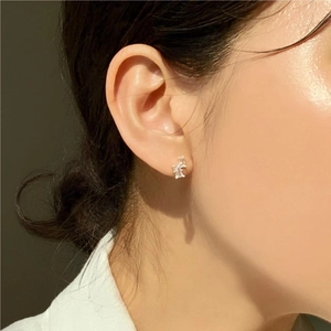 Close-up of square zircon stud earrings with gold base worn by a model in natural light