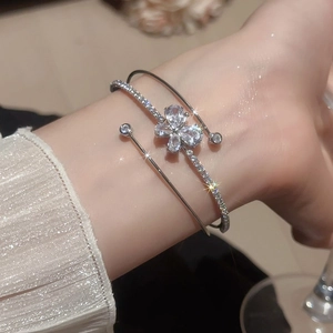 Dettaglio ravvicinato di un bracciale rigido in argento con accenti di farfalle in zircone